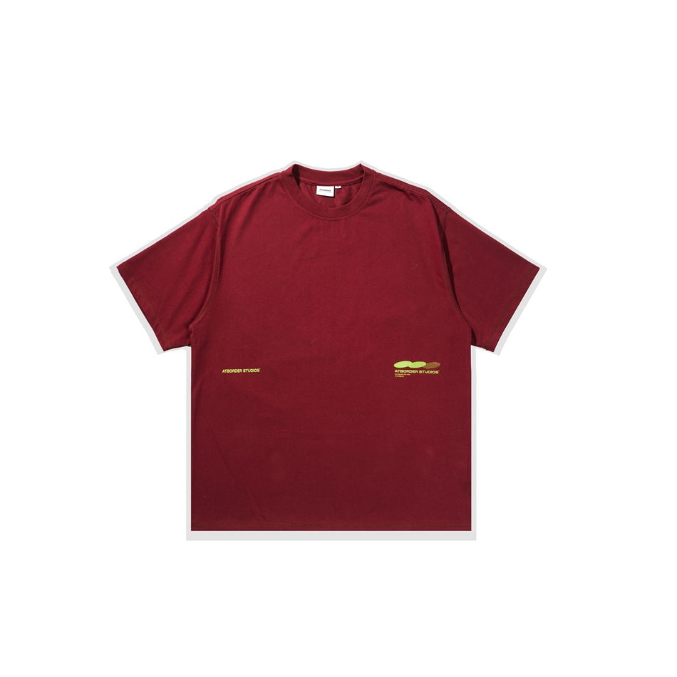 Red short-sleeve crew-neck t-shirt flat lay with small green printed text and oval graphic near the lower hem