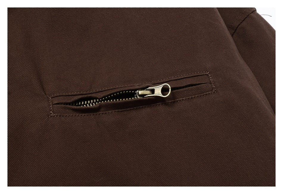 Close-up of a horizontal zip pocket on the dark brown jacket, with a metal zipper pull.
