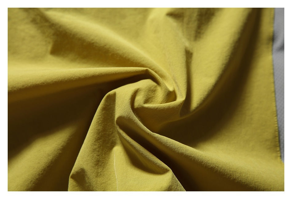 Close-up of mustard-yellow garment fabric gathered into soft folds.