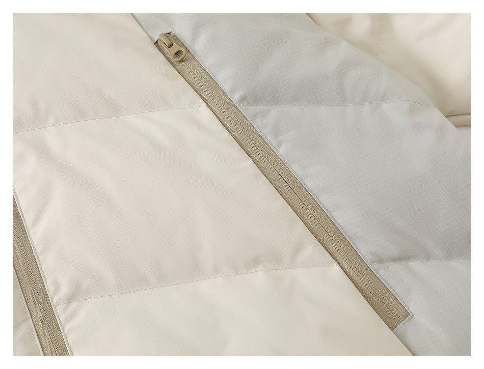 Close-up of a tan zipper crossing cream and light gray panels on a color-blocked jacket.