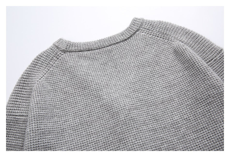 Close view of the upper back of a gray textured cardigan, showing its ribbed neckline and raglan seams.