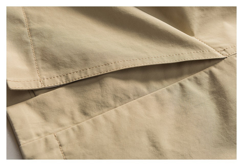 Close-up of a beige garment hem with parallel stitching and overlapping fabric panels.