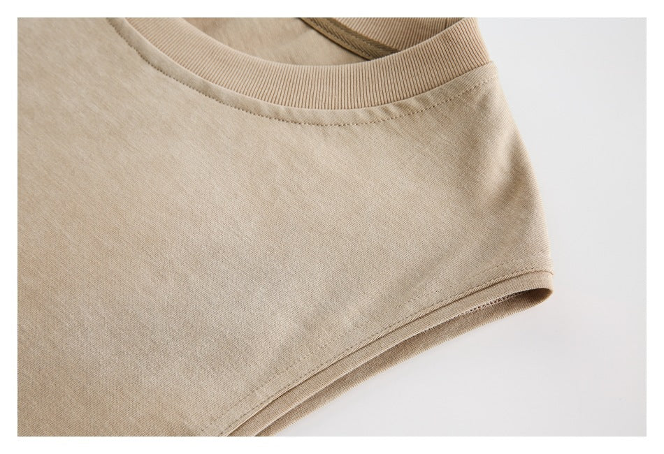 Close-up of beige T-shirt fabric, ribbed crew neck, and a stitched edge.