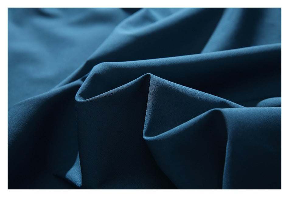Close-up of smooth teal fabric arranged in folds, showing its surface and drape.