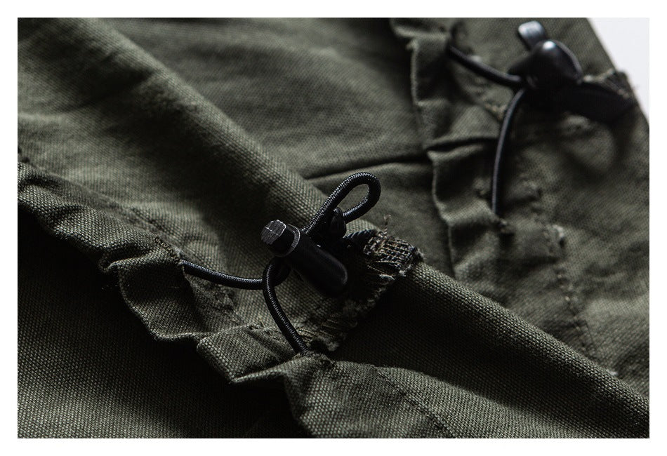 Close-up of an olive garment's gathered seam and black elastic drawcord toggles.