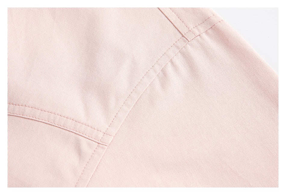 Close-up of pale pink shirt fabric with intersecting stitched seams.