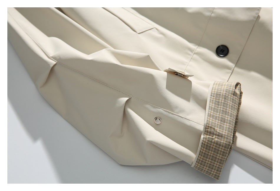 Ivory coat sleeve laid flat, showing a beige plaid cuff lining and a small metal eyelet.