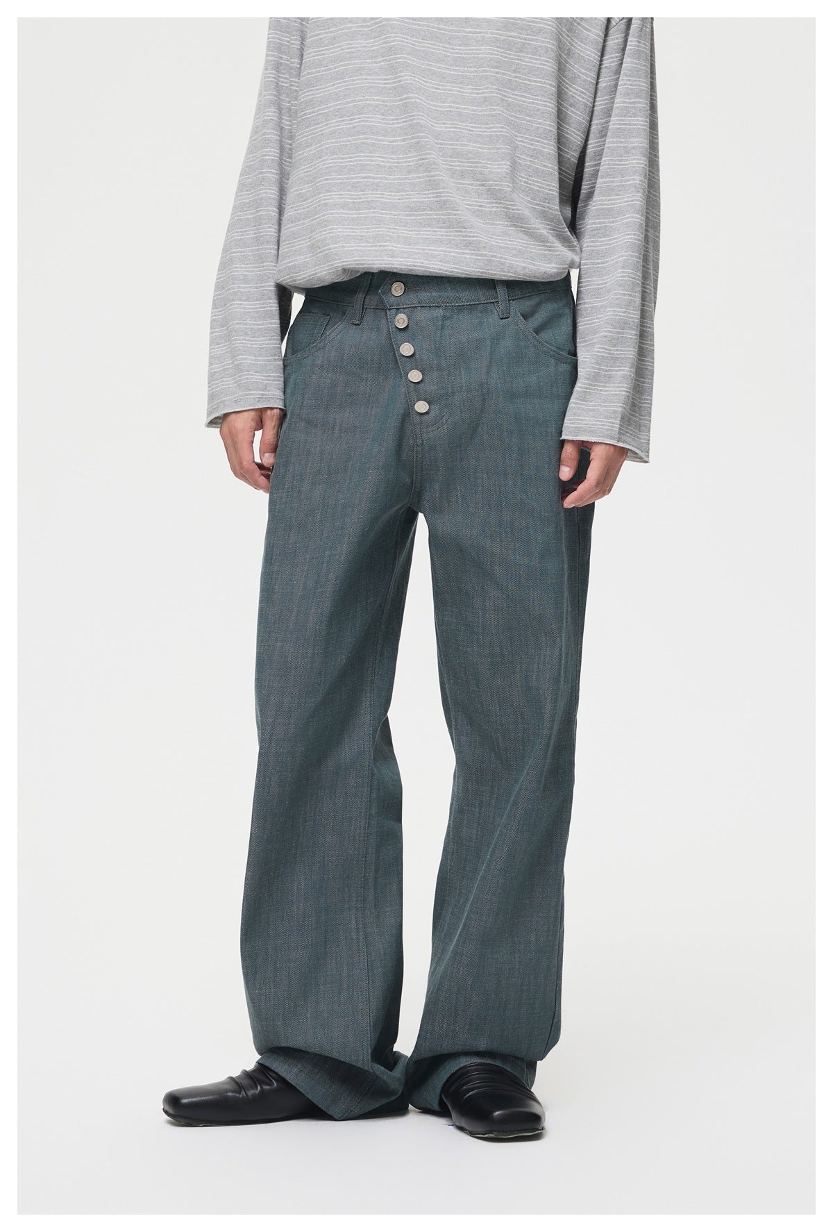 Front view of a model wearing loose blue-gray trousers with a five-button fly and a gray striped top.