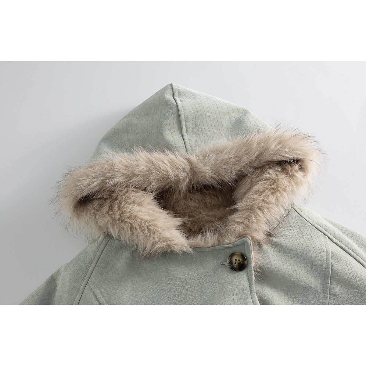Close-up of a sage green jacket hood with a wide beige faux-fur trim and a buttoned front tab.