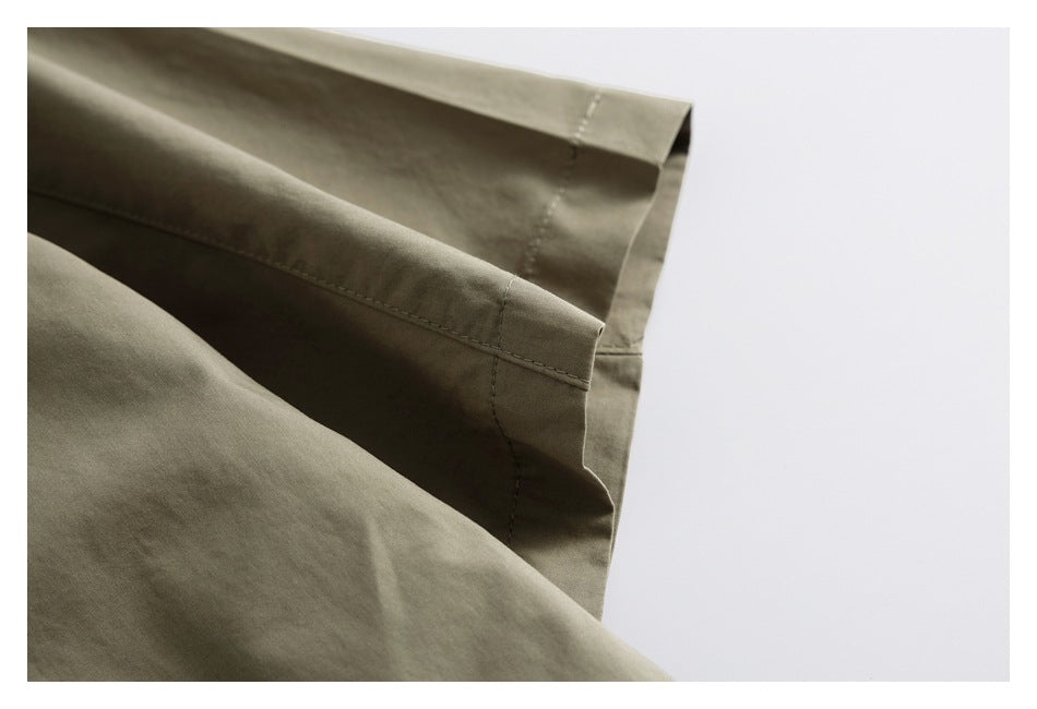 Close-up of olive-gray garment edges with stitched seams and folded hems.