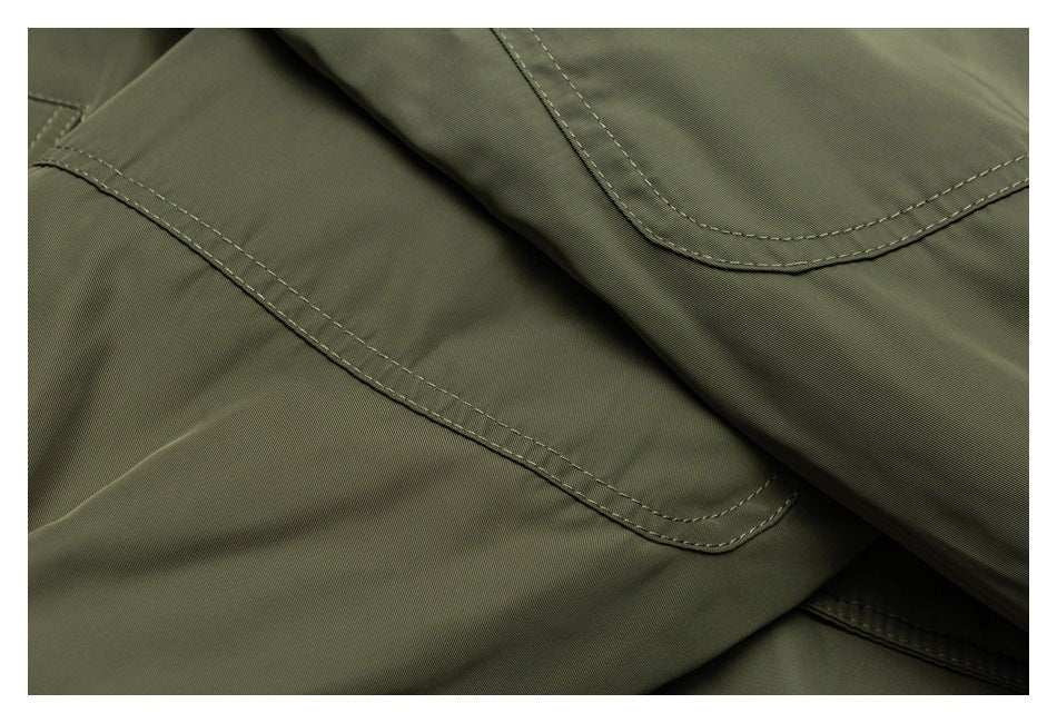 Close-up of overlapping olive jacket panels with curved double-stitched seams.