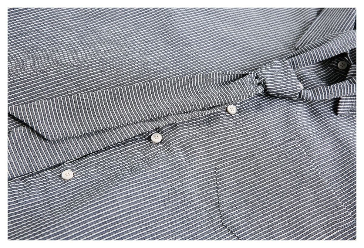 Close-up of a striped shirt collar, button placket, and chest pocket.