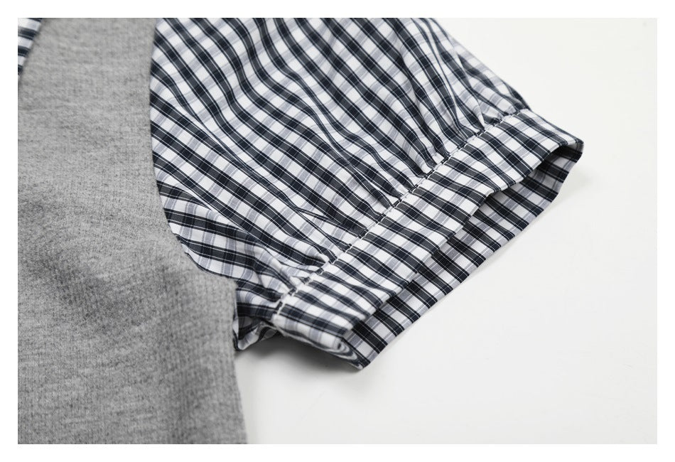 Close-up of the black-and-white plaid short sleeve and cuff beside the gray shirt body.