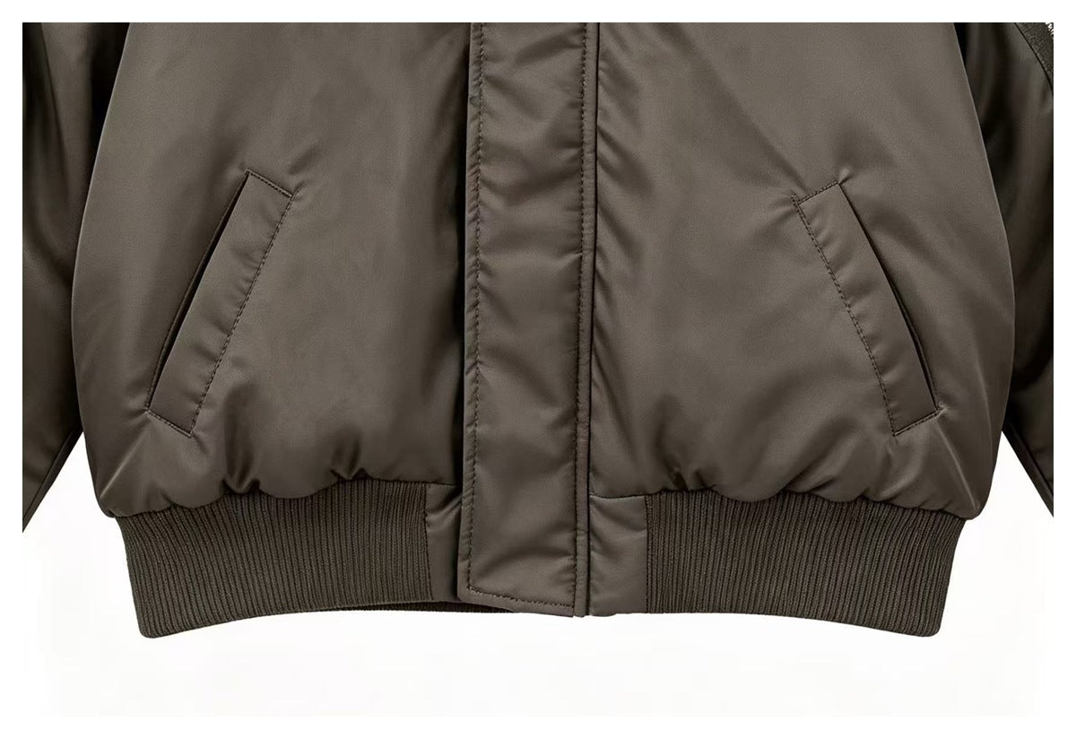 Close-up of the jacket's two angled front pockets, central storm flap, and ribbed waistband.