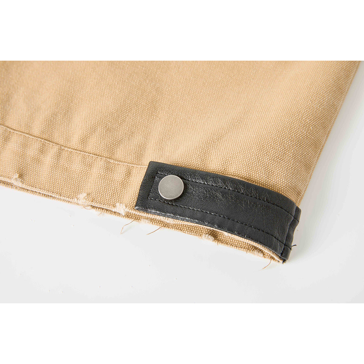 Close-up of a black snap-tab cuff on a tan jacket sleeve.