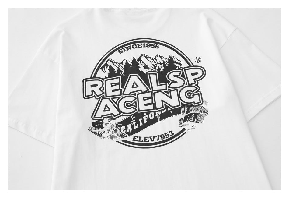 Close-up of a white T-shirt front with a black mountain graphic and bold “REALSP ACENG” lettering.