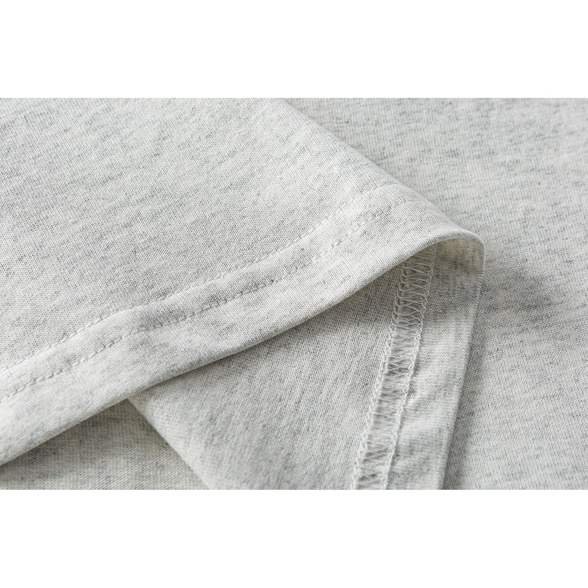 Close-up of a heather-gray shirt hem with double stitching and an overlocked seam.