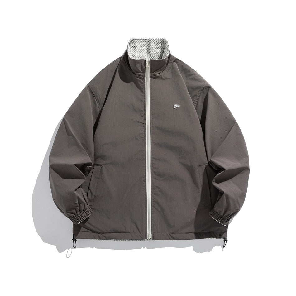 Smooth gray reverse side of stand-collar zip jacket with light zipper, small chest patch and elastic cuffs, flat lay