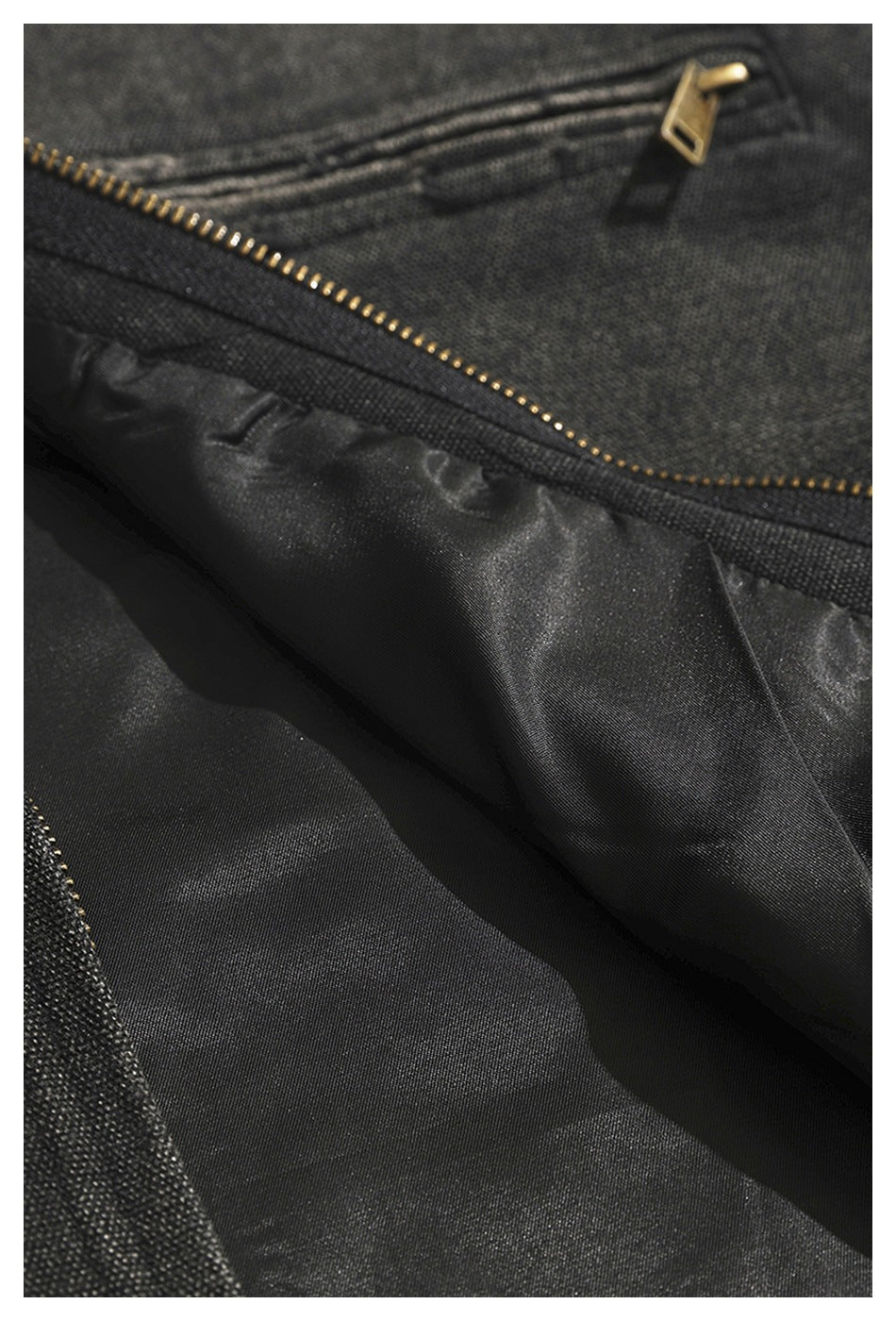 Close-up of a charcoal jacket's black lining and gold-tone zipper.