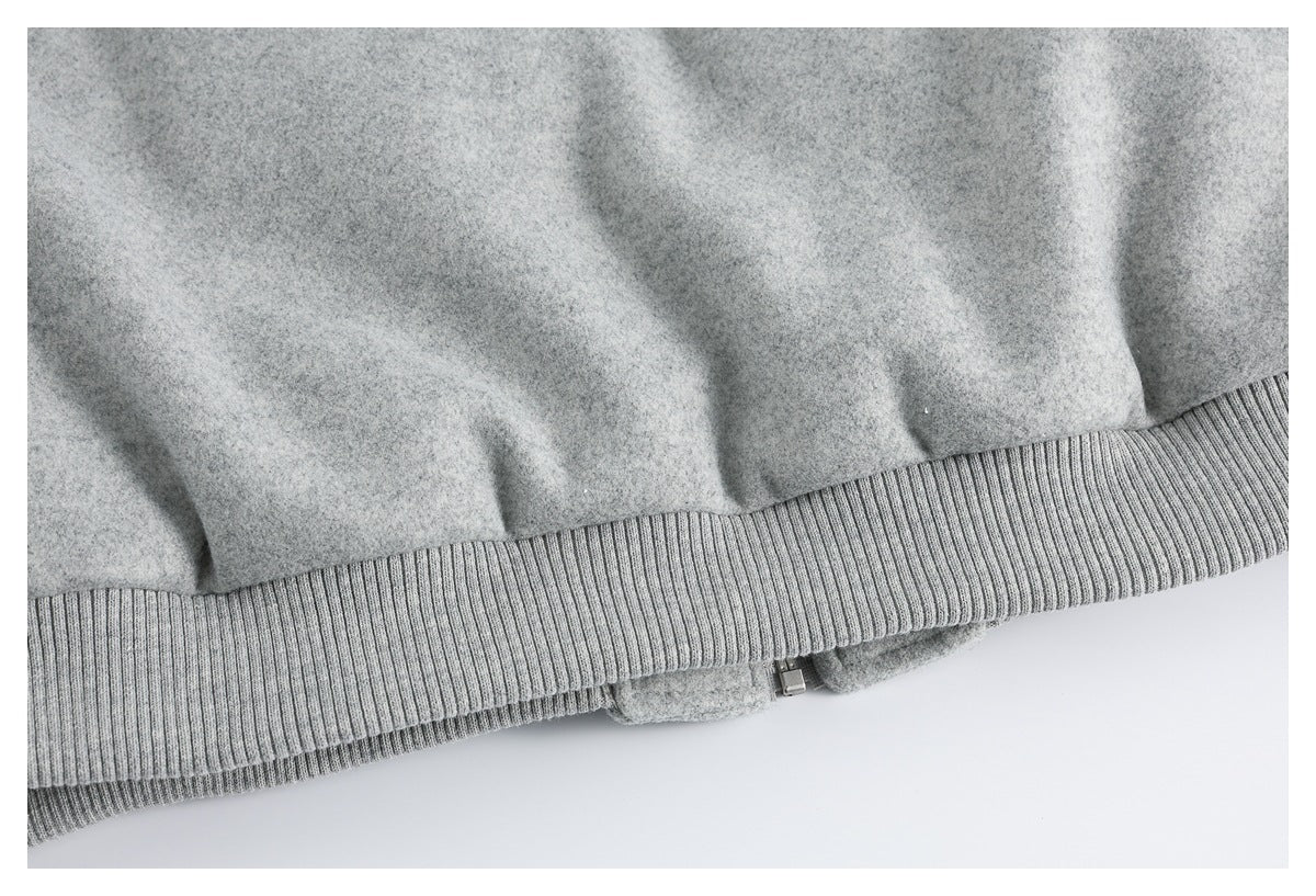 Close-up of the gray jacket's ribbed hem and a partially visible zipper.