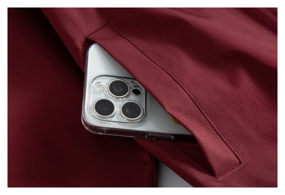 Close-up showing a phone tucked into the slanted pocket of the burgundy jacket.