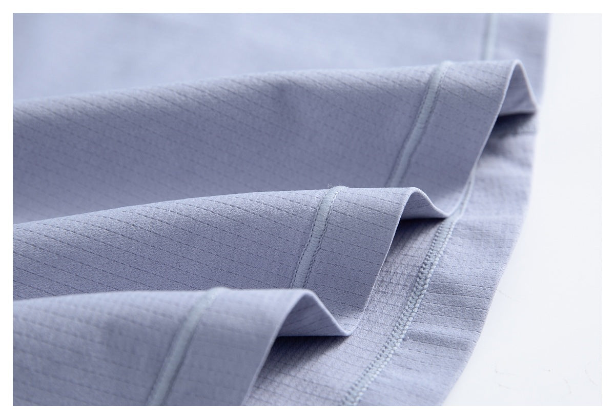 Close-up of folded pale lavender garment edges showing finished hems and parallel stitching.