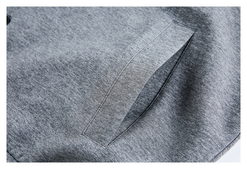 Close-up of a slanted welt pocket on heather gray fabric.