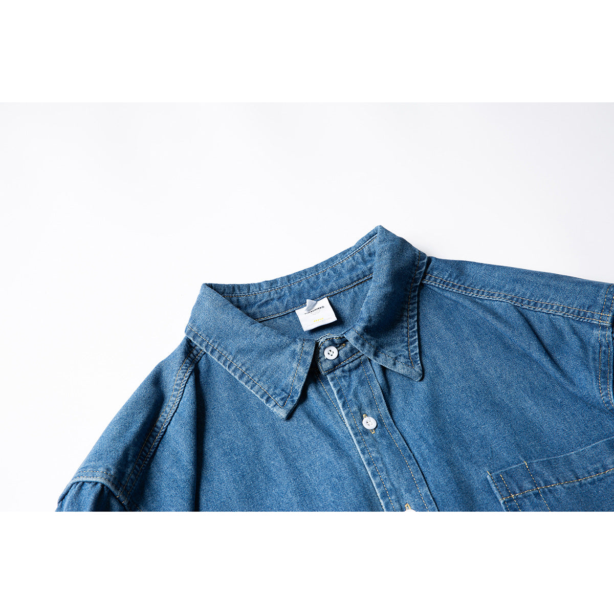 Close-up of a blue denim shirt collar, white buttons, and upper chest on a white background.