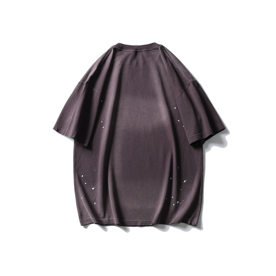 Back of an oversized muted plum short-sleeve T-shirt with small white paint-like splatters near the sides and hem.