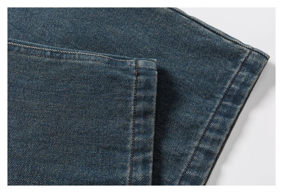 Close-up of dark blue washed denim showing a folded edge, seam stitching, and fading.