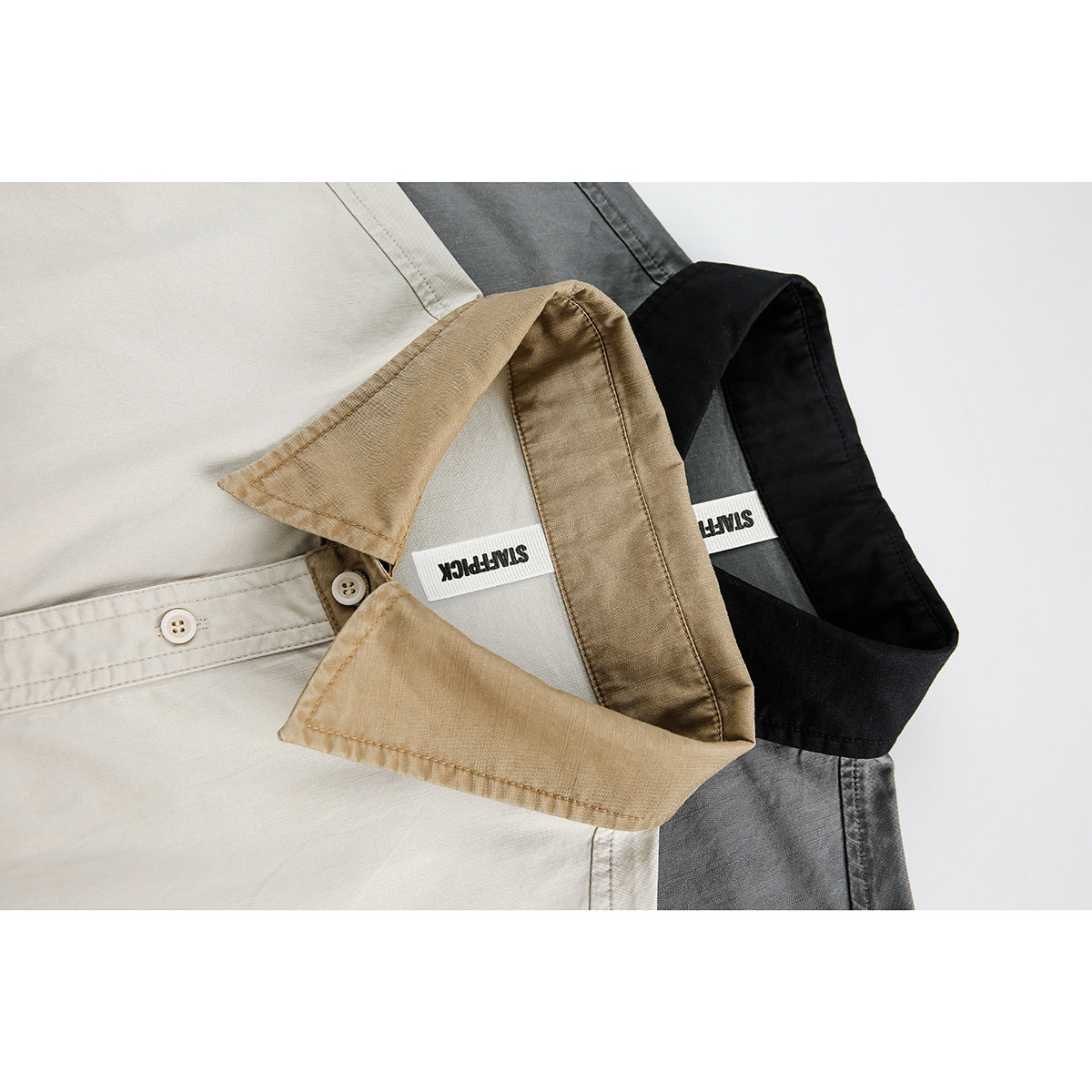 Close-up of overlapping collars on light, gray, and black short-sleeve shirts.