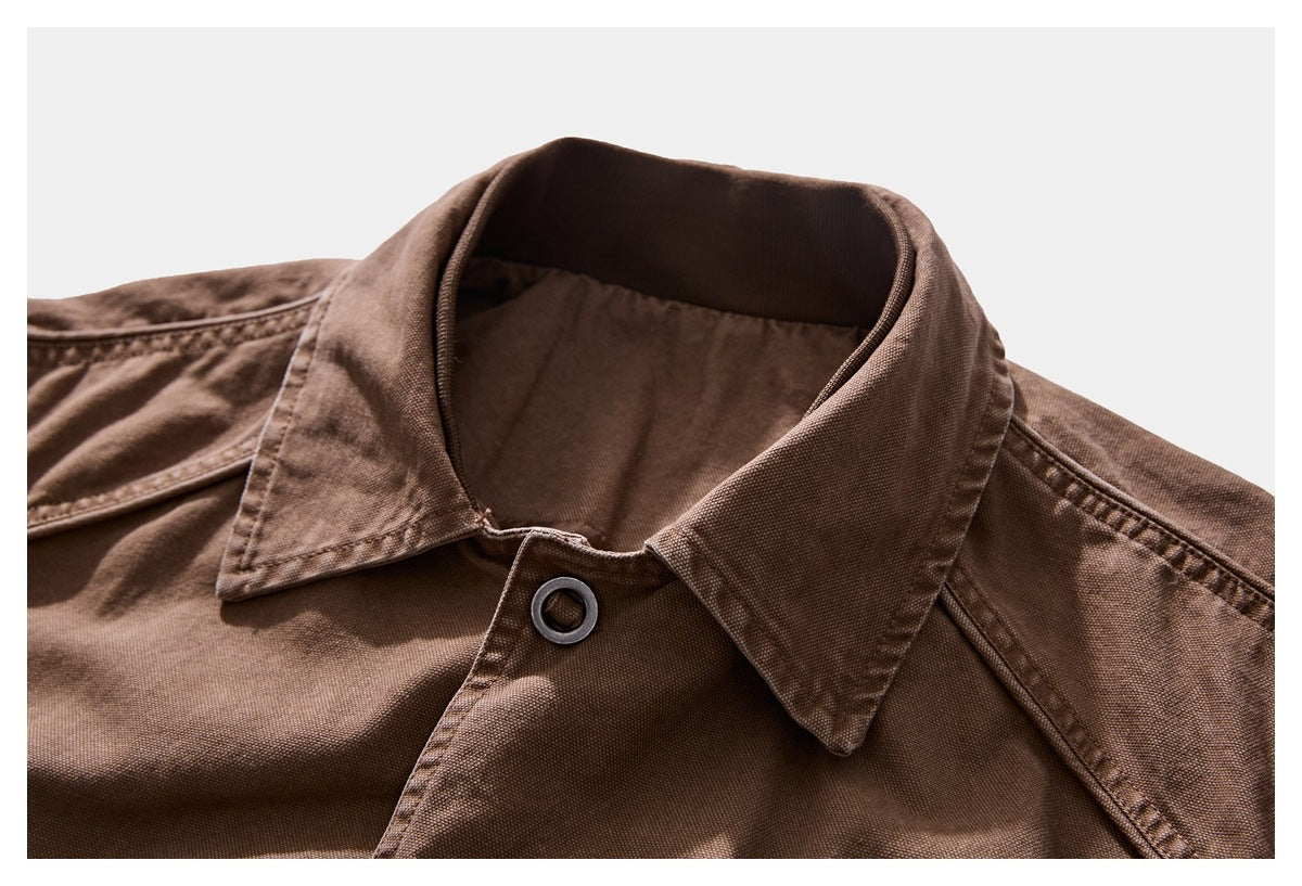 Close-up of a brown jacket collar, neckline, stitching, and dark ring-style button.