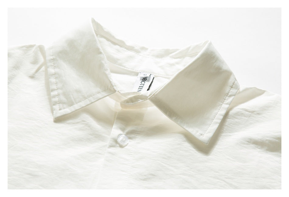 Cropped front view of an ivory button-up shirt with a wide pointed collar and white button.