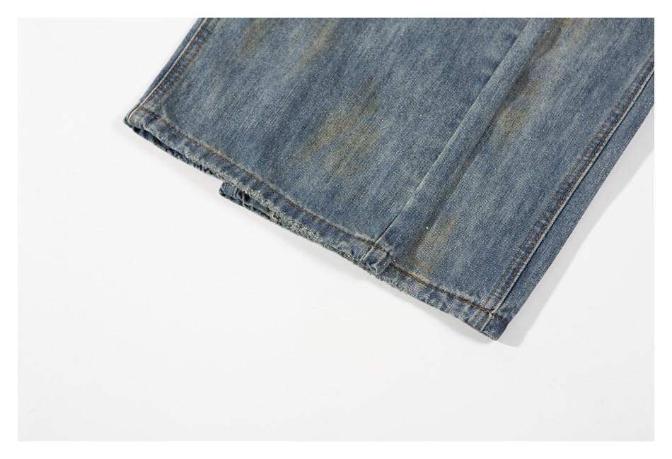 Close-up of the hem and stitching on a leg of faded blue jeans laid flat.