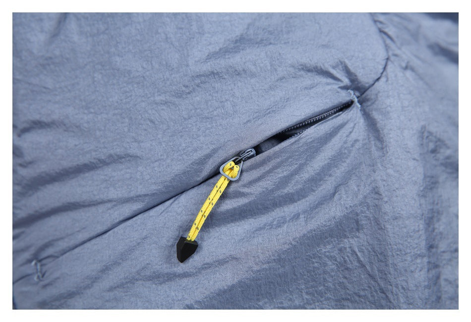 Close-up of a blue-gray zippered pocket with a bright yellow pull cord and black tip.