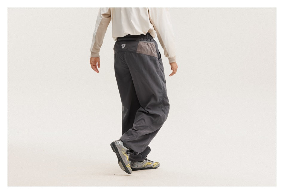 Rear view of a model wearing charcoal-gray pants with a contrasting panel across the back waist.