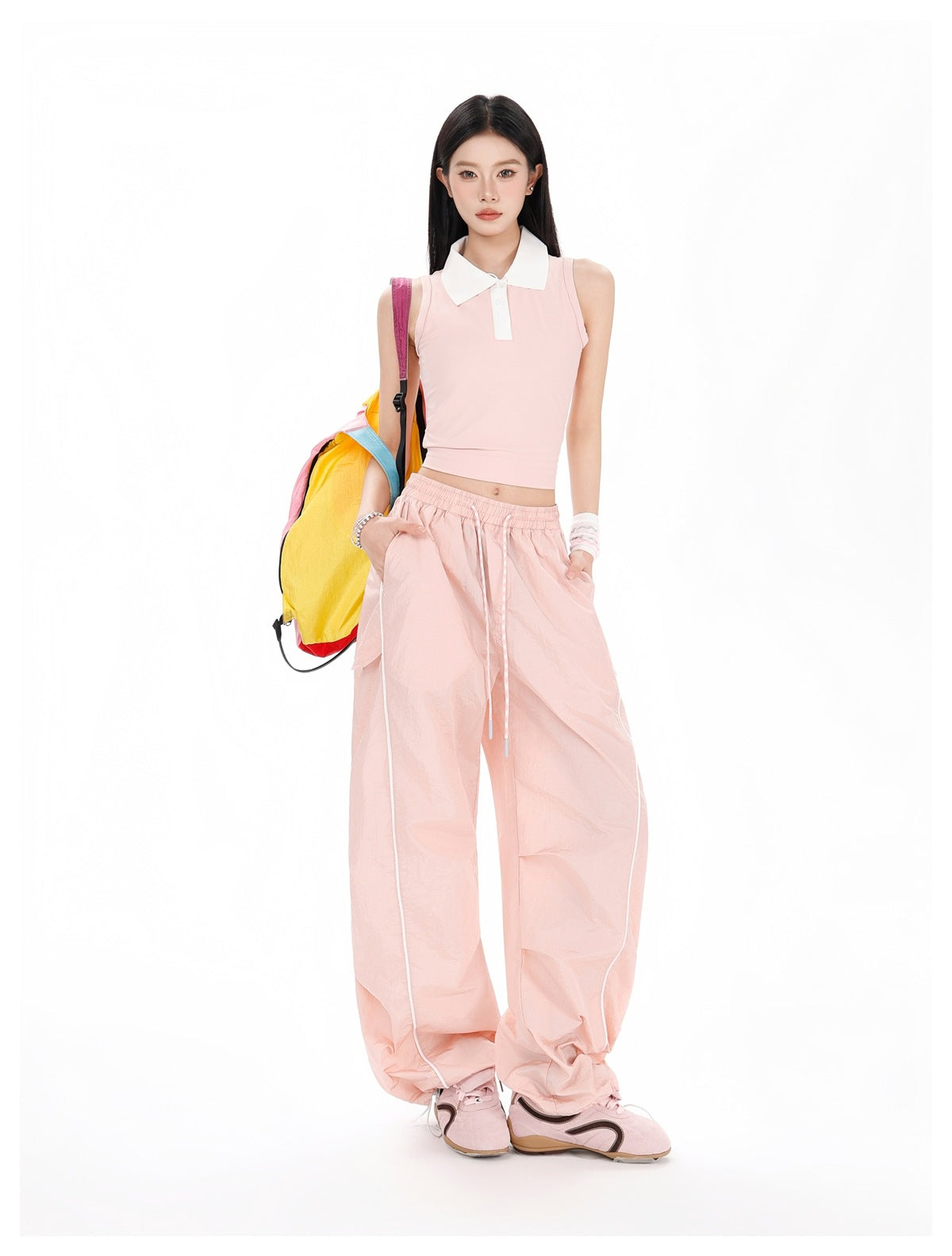 Model wearing a pale pink sleeveless polo top and matching wide-leg pants with an elastic drawstring waist and white piping.