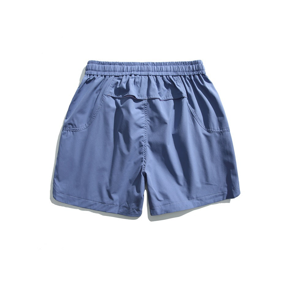 Back view of blue shorts with an elastic waistband, two curved pockets, and a small flap pocket.