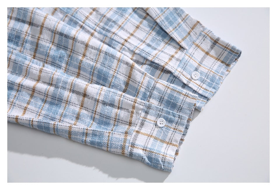 Close-up of a pale blue plaid shirt sleeve with buttoned cuffs.