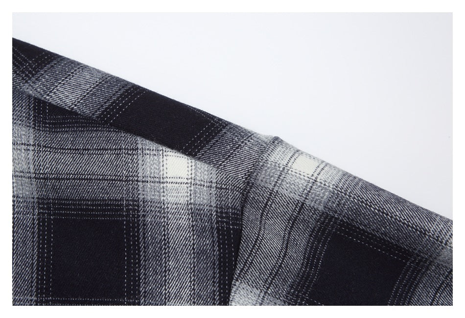 Close-up of the shoulder seam on a black, gray, and white plaid garment.