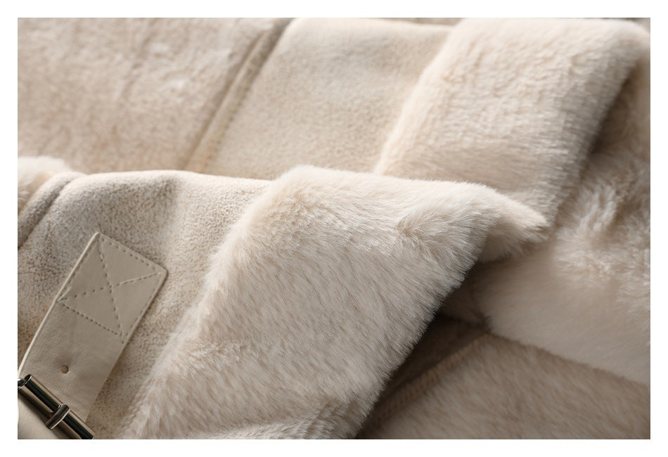 Close-up of a cream plush coat with a stitched belt tab and shiny metal buckle.