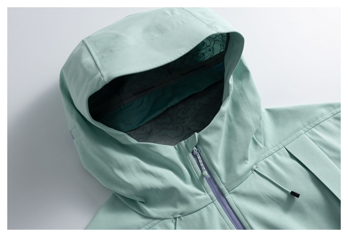 Close-up of a pale mint jacket hood, patterned lining, lavender front zipper, and drawcord.