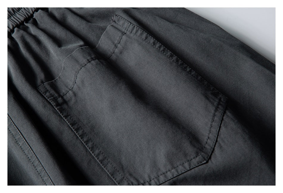 Close-up of charcoal fabric with a stitched rectangular pocket and gathered elastic edge.
