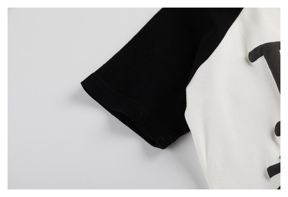 Close-up of a black sleeve beside a white garment panel with part of a black graphic visible.