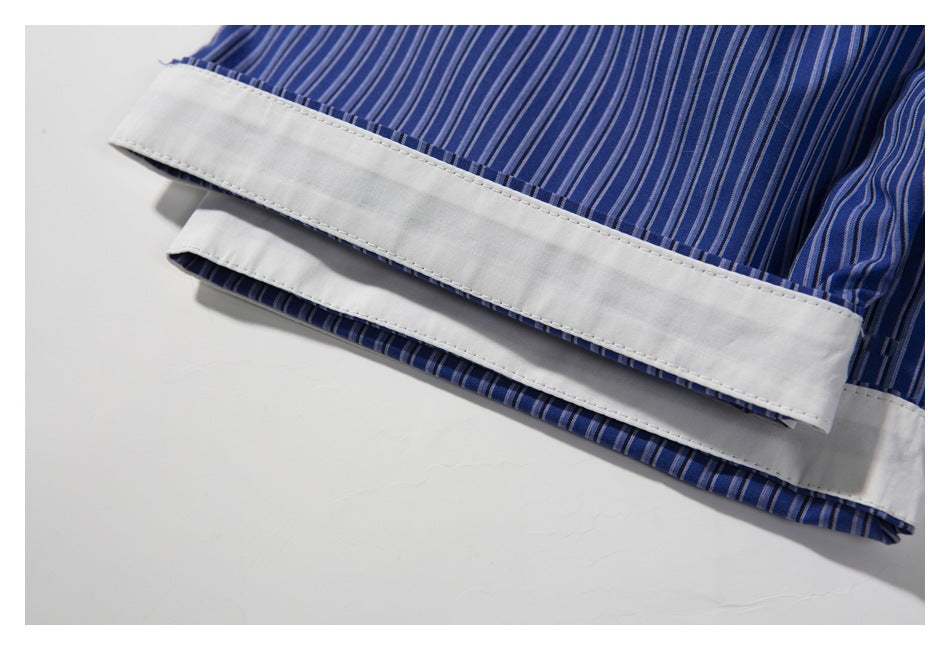 Close-up of a blue vertically striped shirt sleeve with a wide white cuff turned back.