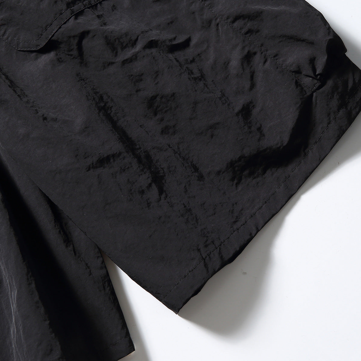 Close-up of black shorts showing the textured fabric, seams and hem.
