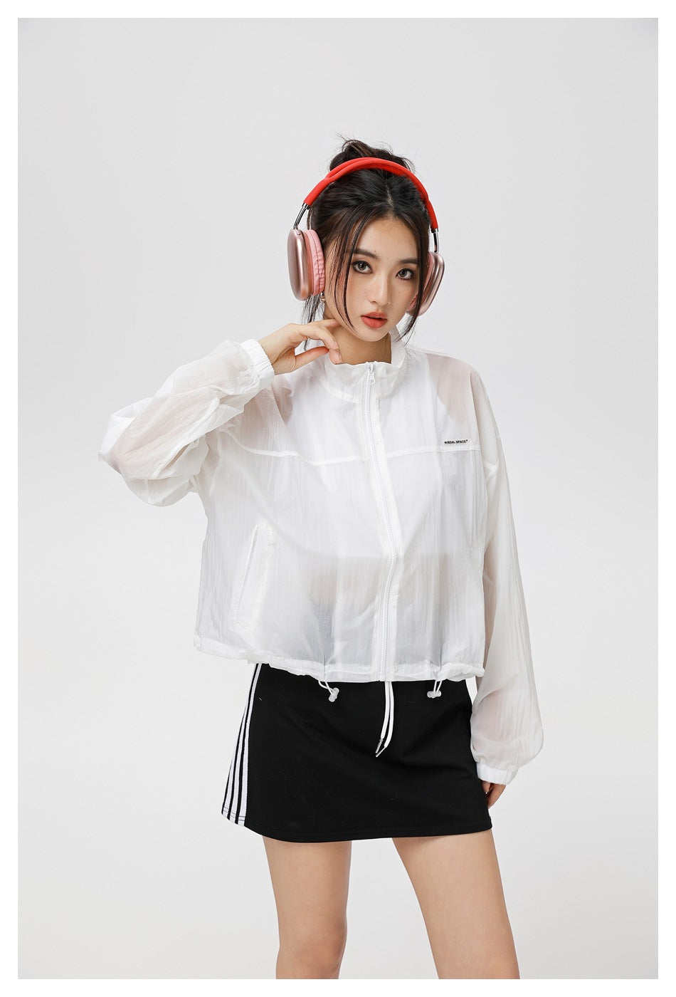 Closer front view of a model wearing a sheer white zip jacket with elastic cuffs and a drawcord hem.