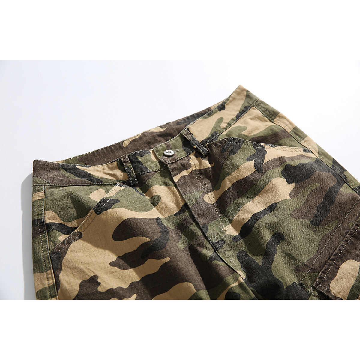 Close-up of the front waistband and pocket area of olive, tan, brown and black camouflage cargo pants.