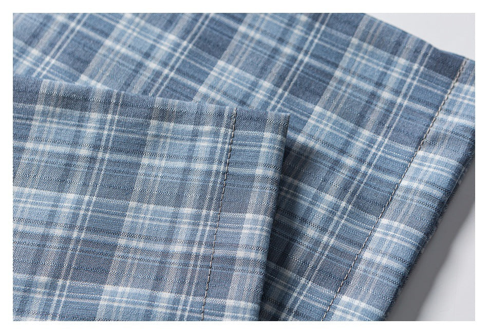 Close-up of overlapping gray-blue plaid shirt fabric with a stitched edge and seam.