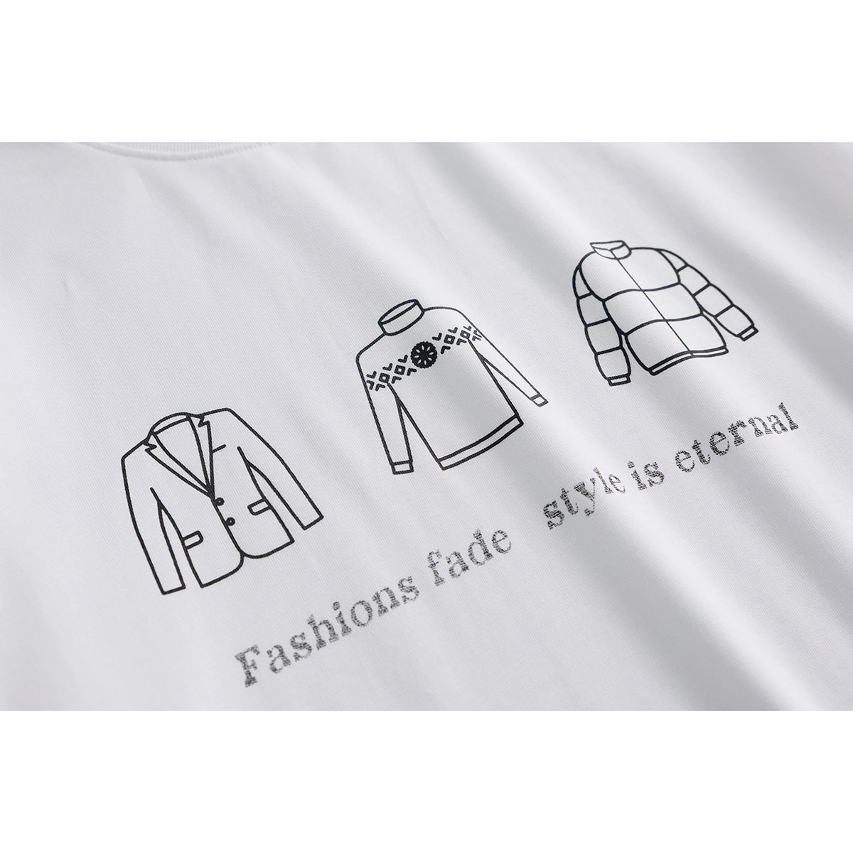 Close-up of a white T-shirt with black line drawings of jackets and the phrase “Fashions fade, style is eternal.”